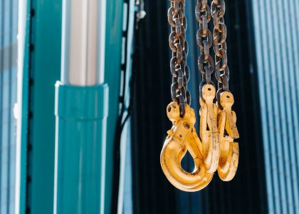 The hooks of the mobile crane near the glass of high buildings.Lots of hooks hanging from chains